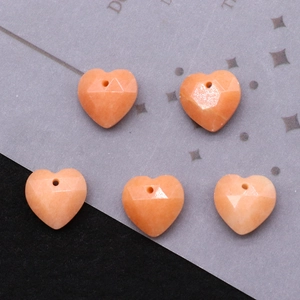 Macro view of five faceted orange-pink heart-shaped natural stone pendants with top holes