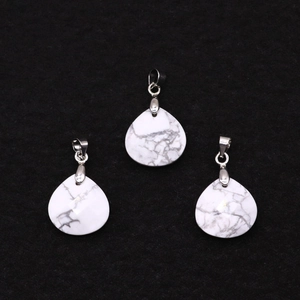 Dettaglio macro di tre ciondoli a goccia in howlite bianca con trama marmorizzata e ganci