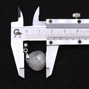 Macro shot of a faceted teardrop moonstone pendant measured by a metal caliper