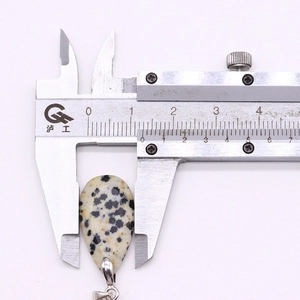 Detailed dimension measurement of teardrop Dalmatian stone pendant with a digital caliper