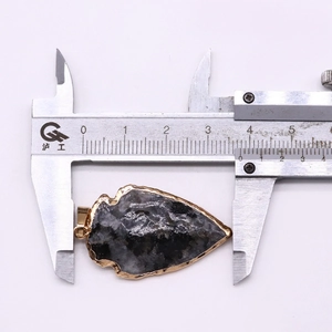 Mesure détaillée d'un pendentif en pierre en forme de flèche avec bordure dorée au pied