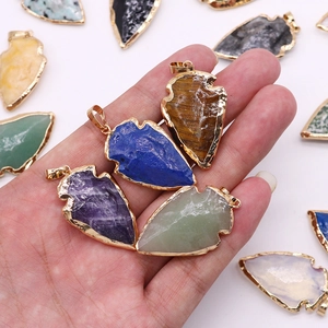 Pendentifs en pierre naturelle en forme de pointe de flèche avec bordure dorée en main