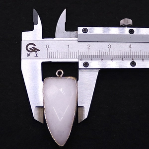Macro shot of a faceted white stone arrowhead pendant showing 25mm width measurement