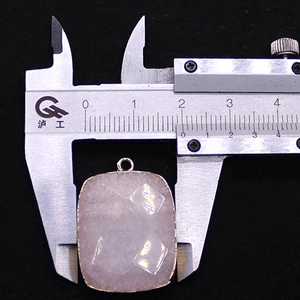 Midiendo el ancho de 18 mm de un colgante rectangular de piedra púrpura con borde dorado