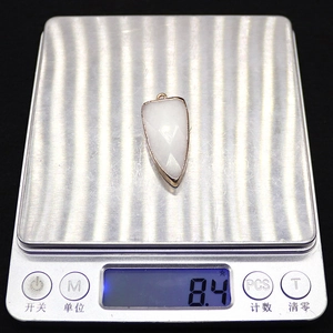 Macro shot of a white shield-shaped faceted gemstone pendant weighing 8.4 grams
