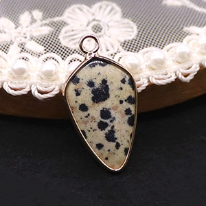 Détail d'un pendentif en jaspe dalmatien avec bordure dorée sur un plateau en perles