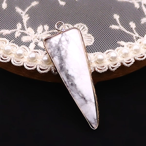 Detalle del colgante triangular de piedra jaspeada con borde de metal chapado en oro