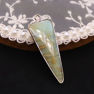 Detalle de un colgante triangular de piedra natural con un borde de metal chapado en oro