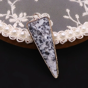 Detalle del colgante triangular de piedra con borde dorado y textura de granito