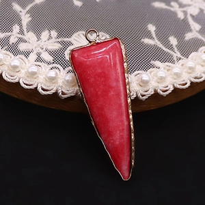 Detalle macro del colgante de piedra triangular roja con elegante marco de metal dorado
