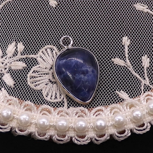 Macro view of blue teardrop natural stone pendant with silver metal bezel and bail