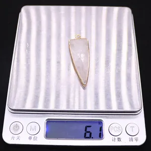 Detailed view of 6.1g light pink triangular stone pendant on a digital scale