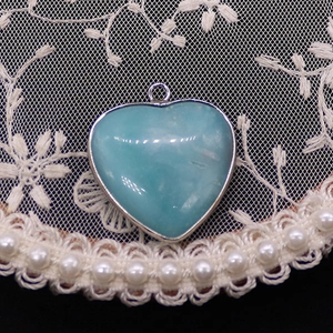 Detail van hartvormige blauwe larimar steen hanger met zilveren metalen omlijsting