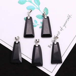 Detailed view of five black trapezoid stone pendants with silver clasps on card