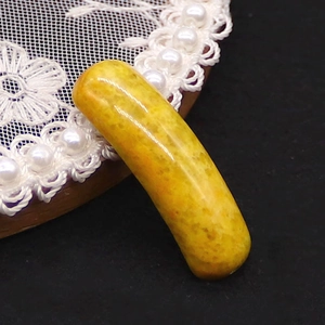 Macro detail of the polished bright yellow natural stone bead connector on a black background