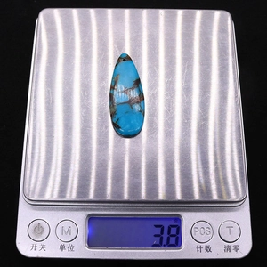 Pendentif goutte turquoise pesant 3,8 grammes sur une balance numérique argentée