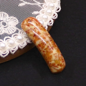 Macro shot of curved natural stone pendant connector with reddish-brown marble texture