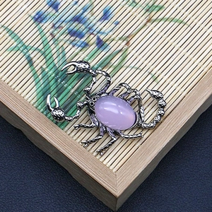Detalle macro del colgante de escorpión con piedra púrpura sobre fondo de bambú