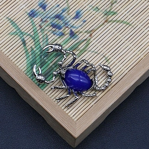 Detalle de colgante de escorpión con piedra azul sobre un fondo de estera de bambú