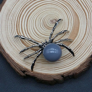 Close-up of a vintage silver spider pendant with a grey gemstone on a wood slice