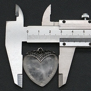 Macro-opname van hartvormige hanger gemeten met schuifmaat die 2,8 cm breedte toont