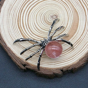 Detailed macro view of a vintage silver spider pendant featuring a pink quartz stone