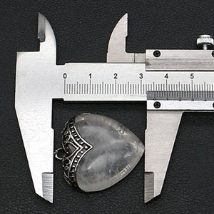 Meten van de hartvormige witte kristallen hanger met metalen rand via een schuifmaat