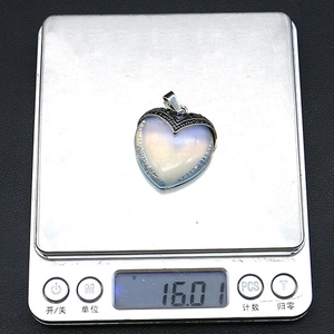 Macro-detail van hartvormige opaal hanger van 16,01 gram op een digitale weegschaal