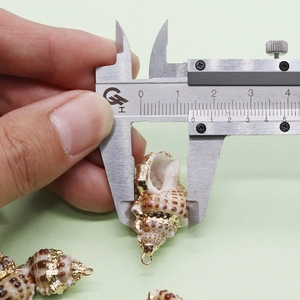 Macro shot of a conch-shaped pendant measured with a caliper for DIY jewelry