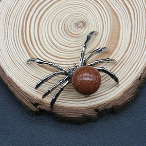 Macro detail of a silver spider pendant with goldstone gemstone body on a wood slice