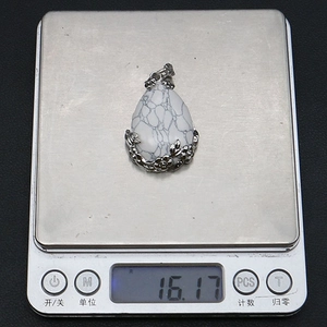Dettaglio del ciondolo a goccia in howlite naturale dal peso di 16,17g su una bilancia