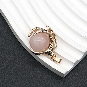 Detalle del colgante de cristal rosa con garra de dragón dorada y anilla superior
