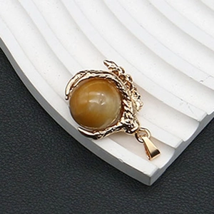 Detalle macro del colgante de garra de dragón con esfera de ojo de tigre y acabado dorado