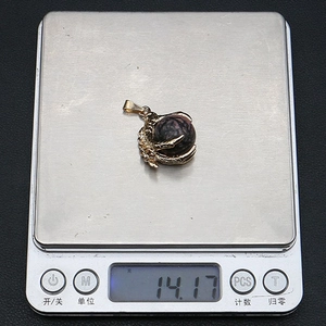Macro detail of natural stone crystal pendant in golden dragon claw being weighed at 14.17g
