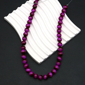 Macro detail of 8mm purple tiger eye beads with silk luster for jewelry making