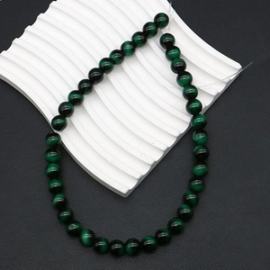 Macro detail of dark green tiger eye beads showing cat-eye effect for DIY jewelry