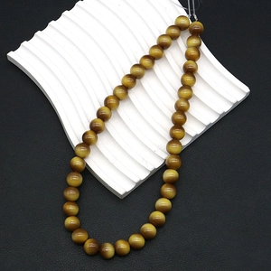 Close-up of brown tiger eye beads on white wave stand and black leather background