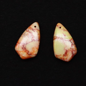 Macro detail of natural stone pendants with red marble patterns and precise top-drilled holes