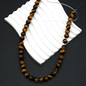 Macro detail of round tiger eye beads showing silky luster and golden brown texture