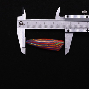 Detail view of colorful striped stone pendant being measured by a caliper tool
