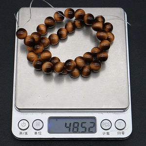 Tiger eye beads on a digital scale showing a precise weight of 48.52g for DIY jewelry