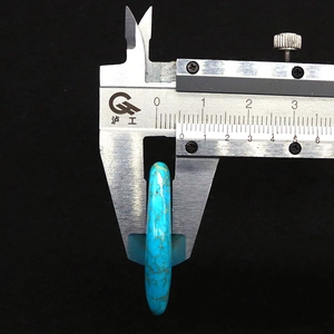 Mesure d'un pendentif turquoise en losange de 9 mm avec un pied à coulisse en métal