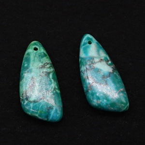 Detailopname van twee turquoise hangers met natuurlijke adering op een zwarte ondergrond