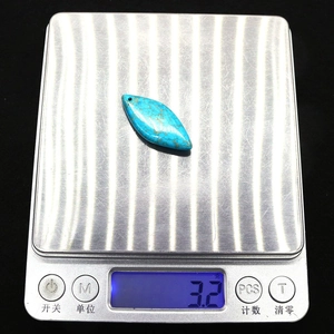 Vue macro d'un pendentif marquise en turquoise de 3,2g sur une balance de précision