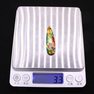 Macro shot of 13x44mm teardrop stone pendant on an electronic scale for weight check