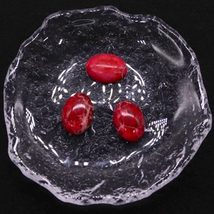 Tres cabujones de jaspe imperial rojo con textura de mármol sobre fondo negro
