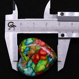 Ripresa macro di un ciondolo in turchese a forma di cuore misurato con un calibro