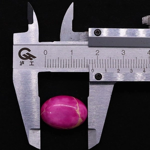 Medición de una piedra imperial ovalada rosa con calibre mostrando el ancho de 18 mm