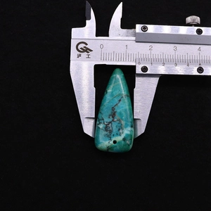 Misurazione della larghezza di 1,4 cm di un ciondolo in turchese triangolare con calibro