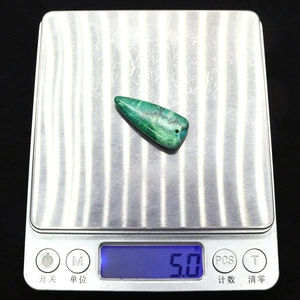 Vista macro di un ciondolo a triangolo in turchese su una bilancia con peso di 5,0g